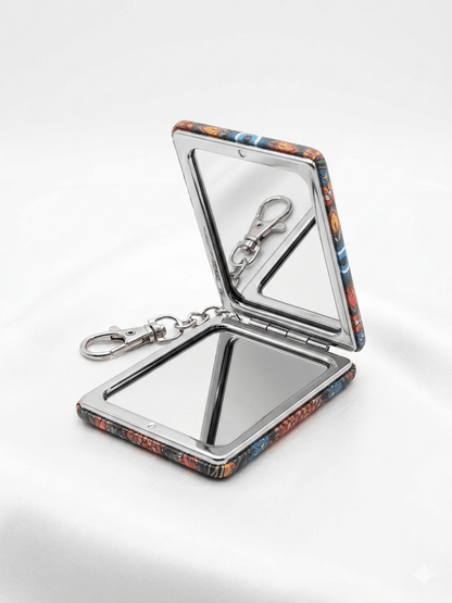 Evil Eye Compact Mirror Keychain with vibrant patterns opened on a soft white background.