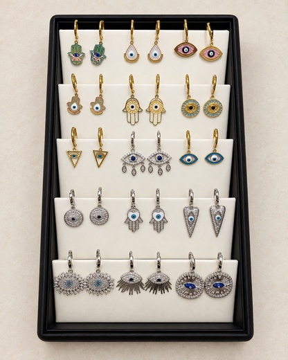 AI-retouched studio photograph of the evil eye and Hamsa earring display, 15 pairs with tray included