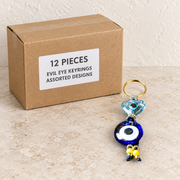 Evil Eye Keyrings - Assorted Designs — Box of 12 — 12 × Evil Eye Keyrings - Assorted Designs. Representative samples beside illustrative wholesale carton.
