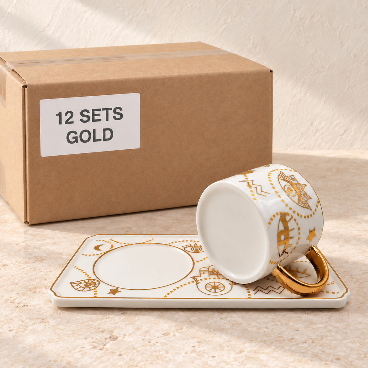 Evil Eye Mugs with Rectangular Trays — Box of 12 — 12 × Gold. Representative samples beside illustrative wholesale carton.