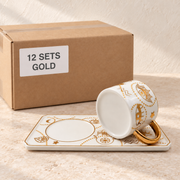Evil Eye Mugs with Rectangular Trays — Box of 12 — 12 × Gold. Representative samples beside illustrative wholesale carton.